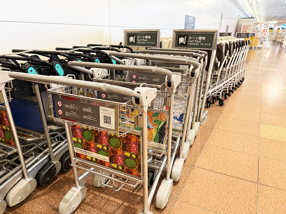 空港内の手荷物カート置き場に整然と並ぶ、アートが施されたデザインカート。