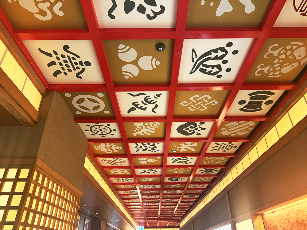 江戸小路の建物天井に施された、日本の伝統的な縁起物が描かれた格子天井の装飾。