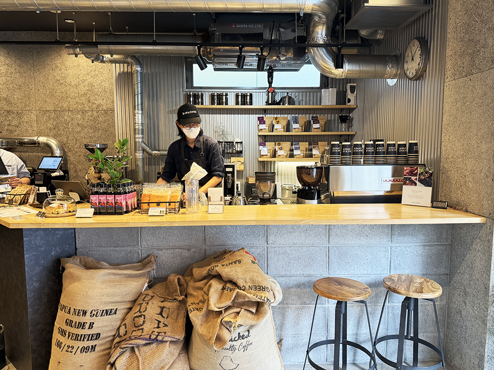コーヒー豆の麻袋が飾られたバックルコーヒーのスタイリッシュな木製カウンターと店内