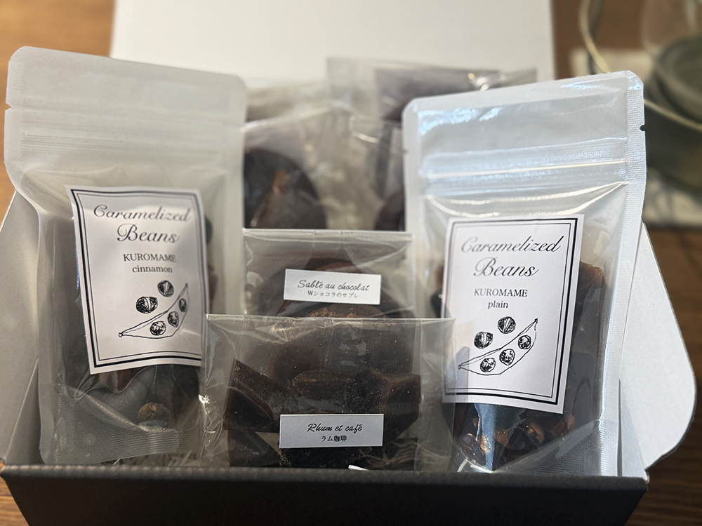 ARTRIA(アルトリア)のとっておきの黒いお菓子ギフトボックス。お豆のキャラメリゼや米粉のサブレ、ケーク、ラム珈琲の琥珀糖がシックな黒い箱に詰め合わされた様子