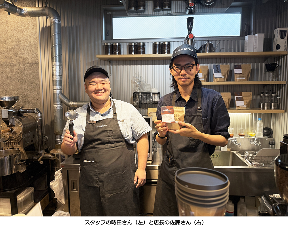 笑顔でコーヒー豆を持つバックルコーヒーの佐藤店長とスタッフの時田さん