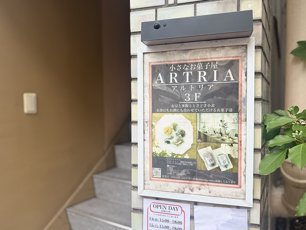 下丸子駅から徒歩3分のビル1階にある「小さなお菓子屋 ARTRIA(アルトリア)3F」の案内看板と営業日を知らせるオープン告知の貼り紙