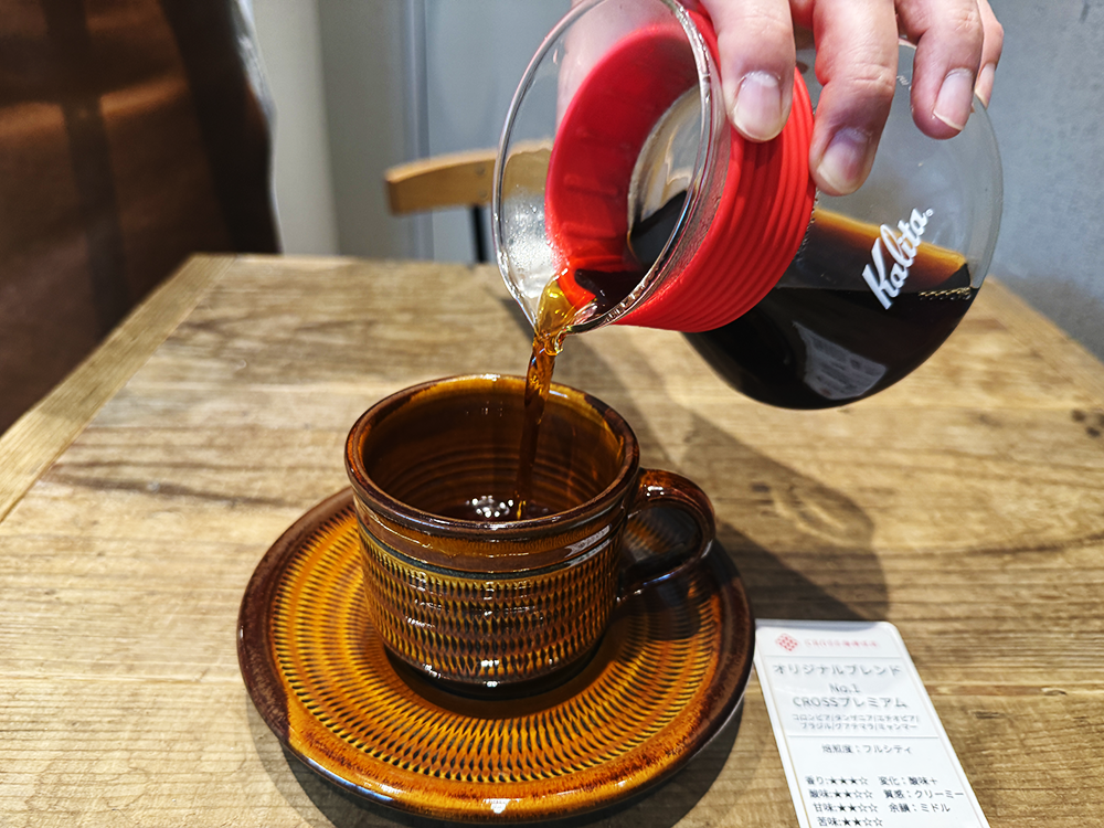 カリタのガラスサーバーから飛び鉋模様のシックな飴色のコーヒーカップへコーヒーを注ぐ様子