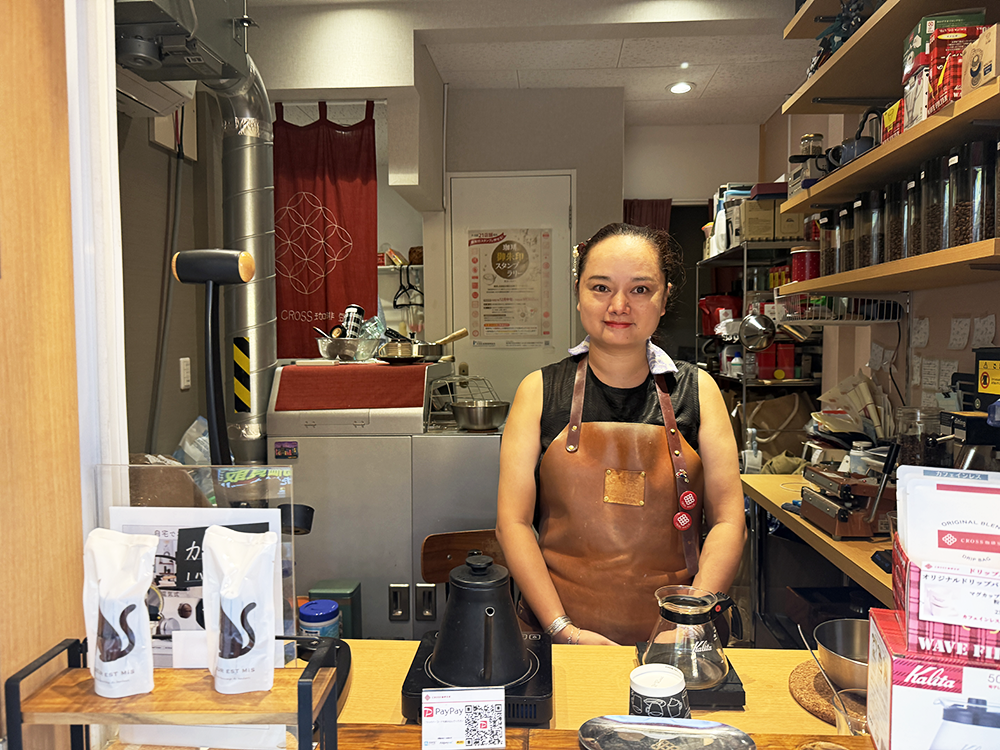 クロス珈琲豆店の店頭カウンターで笑顔でお客様を迎える中島さんの妻
