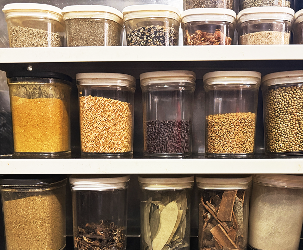 ヤードカレーアンドコーヒーの厨房の棚にずらりと並ぶカレー作りに欠かせないスパイスの入った瓶